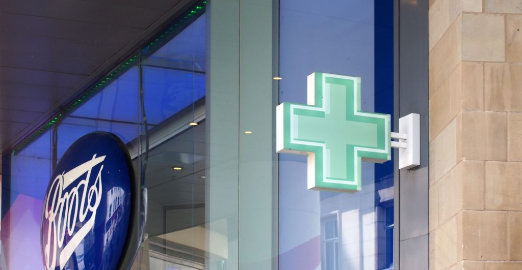 Sign green pharmacy cross above the boots chemists store in brig